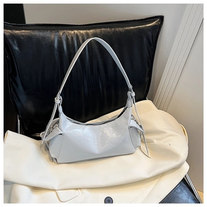 Détail du sac à bandoulière en cuir brillant gris clair avec pompons latéraux décoratifs