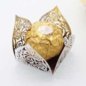 Macro shot of laser-cut gold rose pattern cupcake wrapper and chocolate liner decoration
