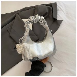 Silver pleated hobo bag with pearl lace charm and chain strap on grey fabric