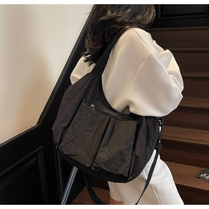 Detail of minimalist black nylon messenger bag with double pockets and wide strap
