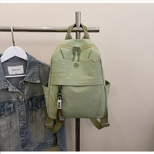 Detail of light green waterproof nylon backpack featuring a round logo and side pocket