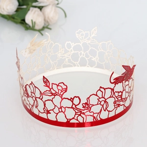 Close-up of laser-cut cake border with red hollow flower and bird patterns