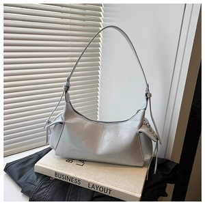 Détail du sac à main gris en forme de croissant avec cordons latéraux sur fond de mode chic