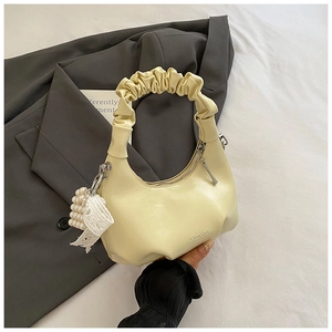 Detail of hobo bag with pleated handle, pearl lace bow charm, and embossed logo