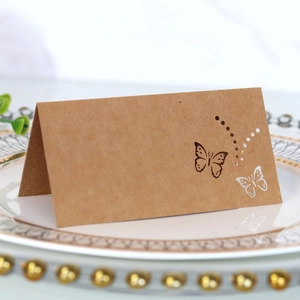 Close-up of laser-cut butterfly kraft paper place card on a white porcelain dinner plate
