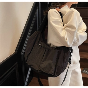 Side view of large black nylon utility crossbody bag showing functional pockets and drape