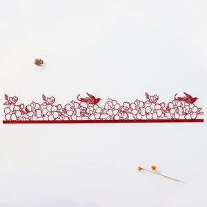 Macro detail of red laser-cut floral and bird cake lace decoration on white background