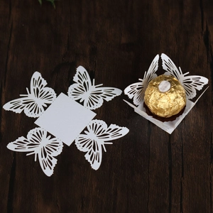 Laser-cut white butterfly favor box detail with intricate wing patterns on wood surface
