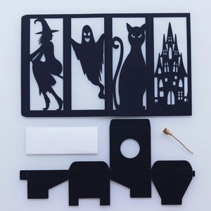 Detail of laser-cut Halloween lanterns with witch, ghost, and cat motifs on black cardstock