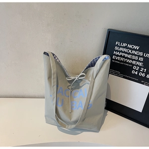 Détail du sac cabas gris avec imprimé lettre bleue et doublure intérieure à carreaux