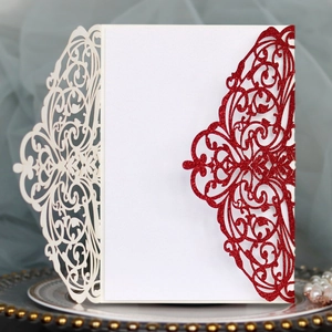 Detailed close-up of intricate laser-cut wedding invitations with glitter finish