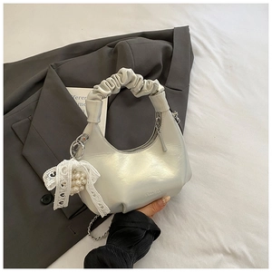 Detailed macro view of silver metallic crescent bag with lace bow and pearl charm