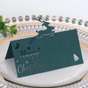 Detail der lasergeschnittenen grünen Weihnachtstischkarte mit Rentier und Baum auf Teller