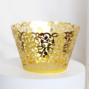 Close-up of golden mirror laser-cut cupcake wrappers with intricate vine hollow patterns