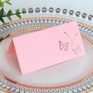 Macro view of a pink pearlescent butterfly laser-cut place card on a white dinner plate