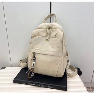 Detail view of the beige casual backpack with adjustable straps and decorative keychain