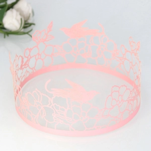 Detailed laser-cut pink paper cake wrap featuring intricate floral and bird patterns