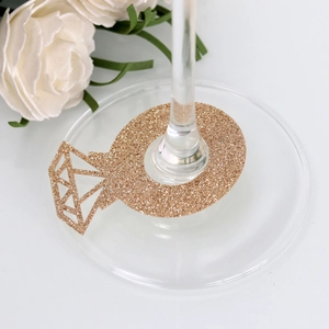 Close-up of golden glitter diamond ring wine glass marker at the base of a clear stemware