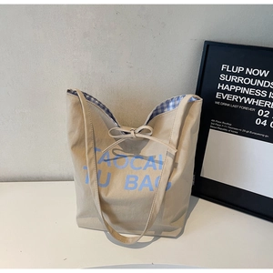Détail du sac cabas en toile avec logo imprimé bleu clair et nœud décoratif élégant