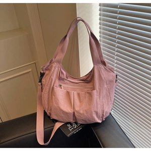 Detail of pink nylon tote bag showing pleated fabric texture and functional pockets