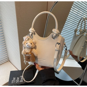 Detailed shot of white crocodile texture bucket bag with cute bear charm and handle