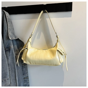 Détail du sac à bandoulière croissant jaune clair avec liens en cuir sur veste en jean