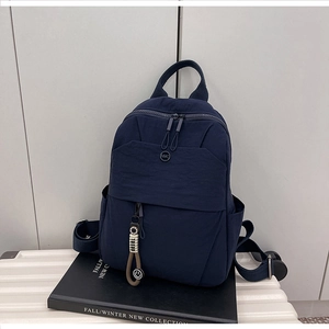 Detail of navy nylon backpack with NMC logo and smiley pendant on a suitcase