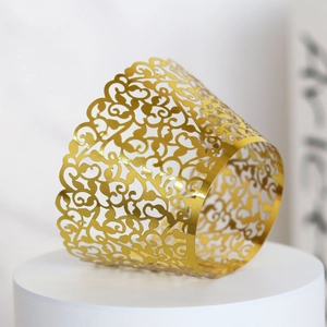 Close-up of golden mirror laser-cut cupcake wrappers with intricate vine floral patterns