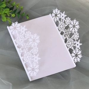 Macro detail of white laser-cut snowflake invitation cover for Christmas on gauze background