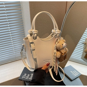 Detail of white crocodile texture bucket bag with cute bear charm and metal buckle