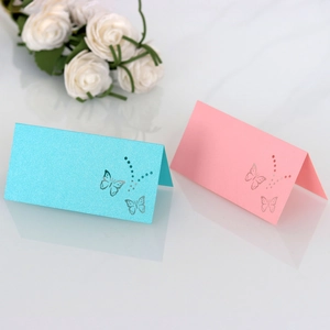 Close-up of pink and blue butterfly laser-cut place cards on a white mirror surface