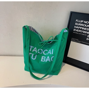 Détail du sac cabas en toile verte avec lettrage imprimé et doublure à carreaux bleus