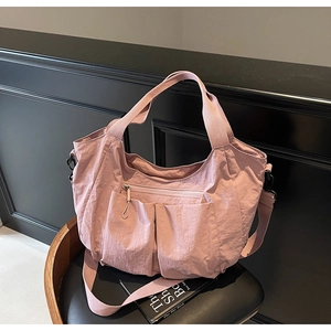 Detail of light pink waterproof nylon tote bag with multiple pockets and adjustable strap