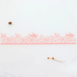 Detail of pink laser-cut cake border featuring intricate floral and bird hollow patterns