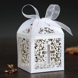 Detail of white laser-cut favor box with cross pattern and white organza ribbon