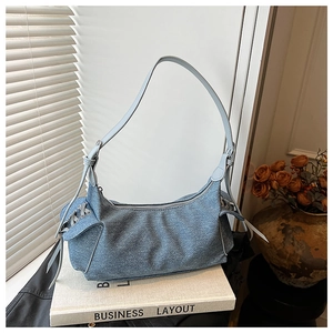 Détail du sac à épaule en jean bleu montrant les lacets latéraux et le tissu délavé