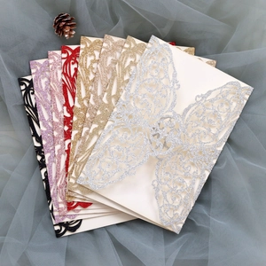 Detailed laser-cut glitter wedding invitation covers in multiple colors with ribbons
