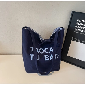 Détail du cabas en toile marine avec texte TAOCATU et doublure intérieure à carreaux