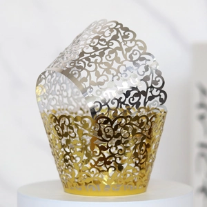 Macro shot of gold and silver laser-cut cupcake wrappers with elegant vine patterns