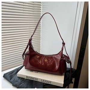 Détail du sac à bandoulière en cuir verni rouge foncé avec forme de croissant élégante