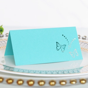 Elegant bright blue butterfly laser-cut place card on a white floral wedding table setting
