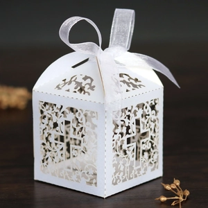 Laser-cut white gift box with cross and floral pattern featuring a white ribbon