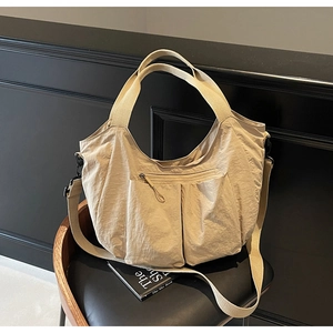 Macro detail of khaki nylon tote bag showing pleated pockets and smooth texture