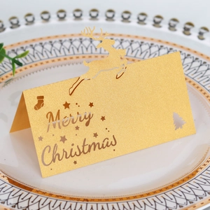 Nahaufnahme der goldenen Laser-Cut Weihnachtskarte mit Rentier-Motiv auf Teller