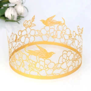 Detail of laser-cut golden crown featuring intricate floral and bird patterns for cakes