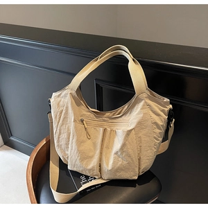 Detail of a large beige nylon hobo tote with multi-pockets and a wide canvas strap