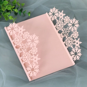 Detail of pink laser-cut snowflake wedding invitation card on soft tulle background
