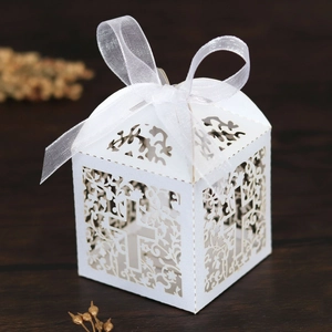 Macro detail of laser-cut wedding favor box with cross pattern and white ribbon bow