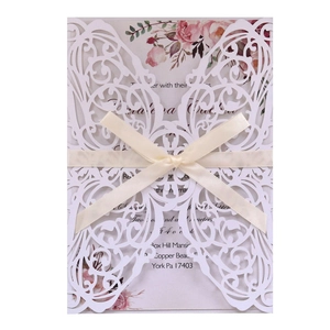 Detailed view of white laser-cut butterfly invitation card with silk ribbon and floral insert