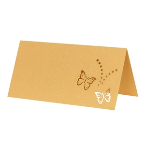 Close-up of golden brown kraft place card with laser-cut butterfly and elegant dotted pattern